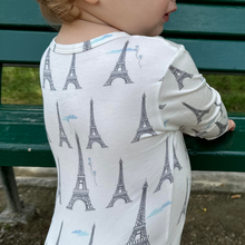 Load image into Gallery viewer, A baby wearing a zippered romper with a slate gray design featuring the Eiffel Tower in Paris, France, accompanied by subtle pale blue balloons and cloud details.
