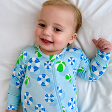 Load image into Gallery viewer, A baby wearing a long-sleeved blue and green zippered romper with a geometric pattern, lying on a white surface.