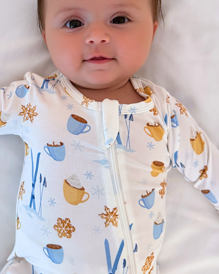 Baby wearing a onesie with coffee-themed design on a neutral background