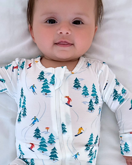 Baby wearing a onesie with a ski pattern on a white background