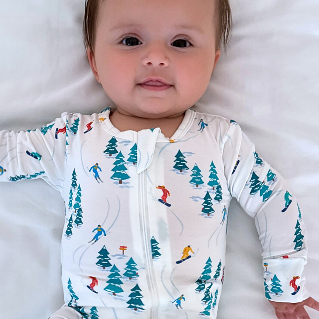 Baby wearing a onesie with a ski pattern on a white background