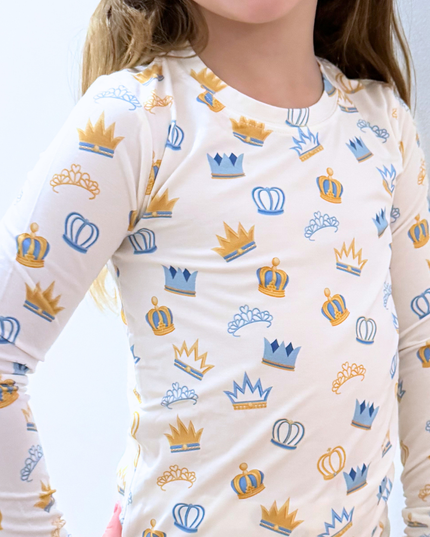 Child wearing a long-sleeve shirt with crown patterns on a white background