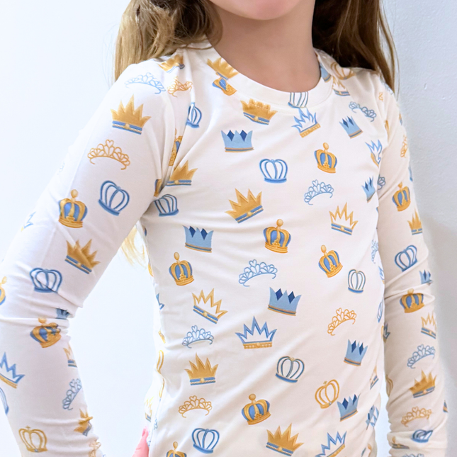 Child wearing a long-sleeve shirt with crown patterns on a white background