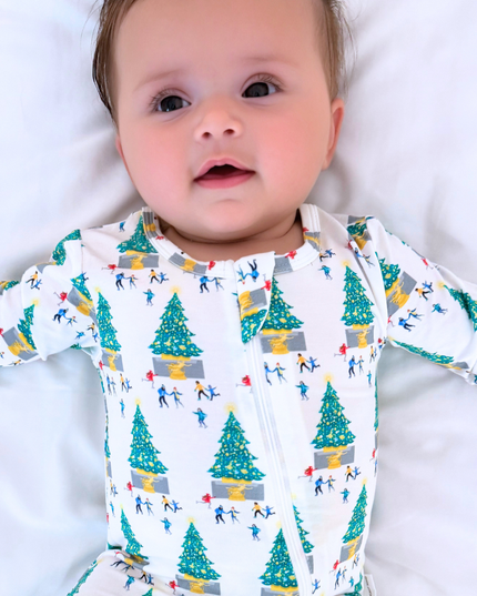 Baby wearing a long-sleeve onesie with a Christmas tree and skier pattern on a white background