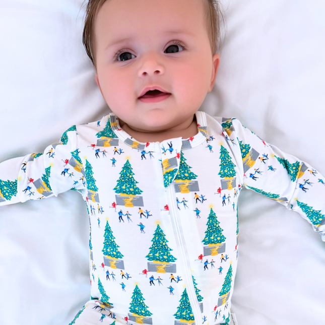 Baby wearing a long-sleeve onesie with a Christmas tree and skier pattern on a white background