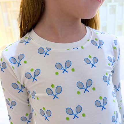 White long-sleeve shirt with blue tennis racket pattern worn by a person.