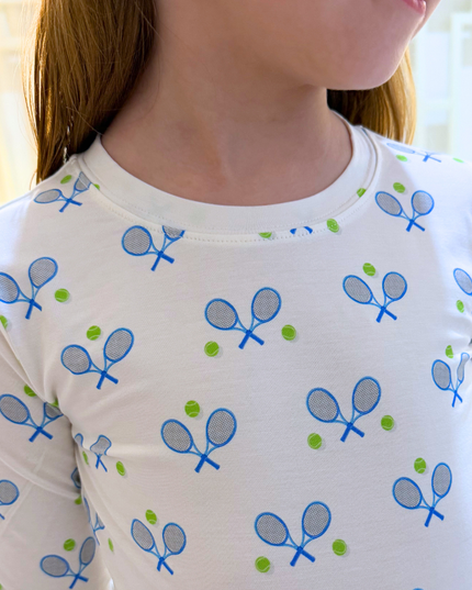 White long-sleeve shirt with blue tennis racket pattern worn by a person.