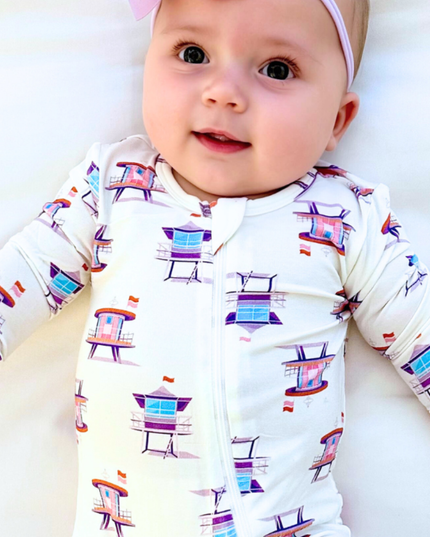 Baby wearing a white onesie with colorful chair pattern on a white background