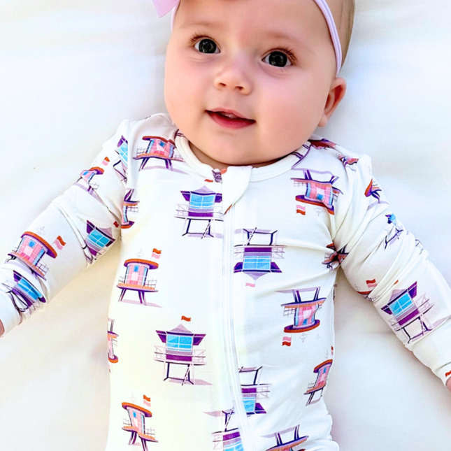 Baby wearing a white onesie with colorful chair pattern on a white background