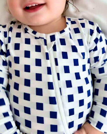 A baby wearing a checkered zippered romper in navy blue and white.