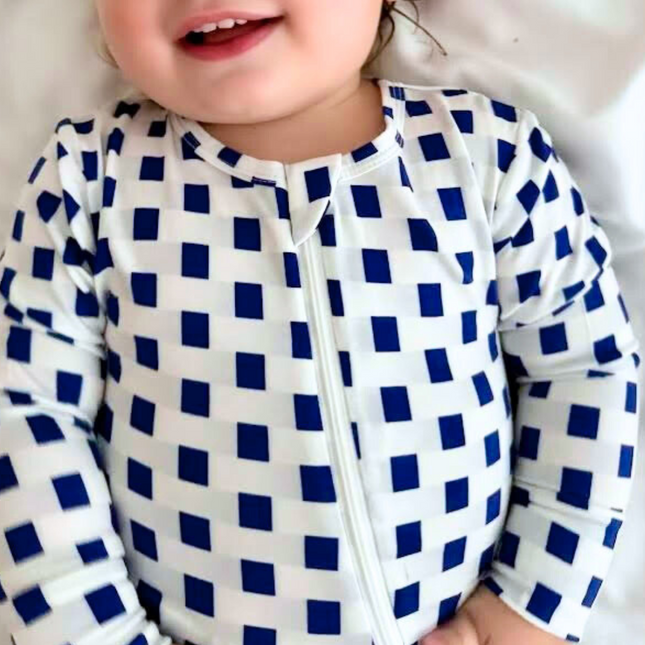 A baby wearing a checkered zippered romper in navy blue and white.