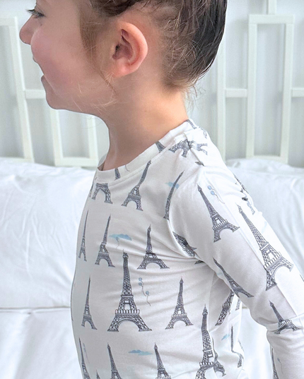 Child wearing a long-sleeve shirt with Eiffel Tower pattern against a white background