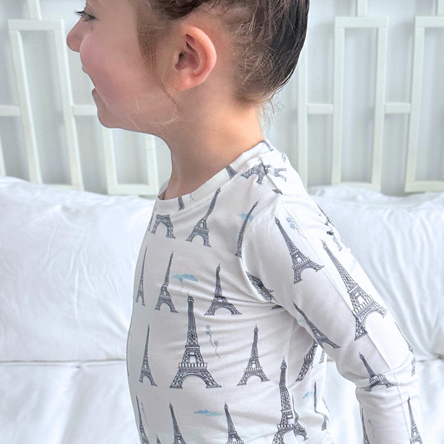 Child wearing a long-sleeve shirt with Eiffel Tower pattern against a white background