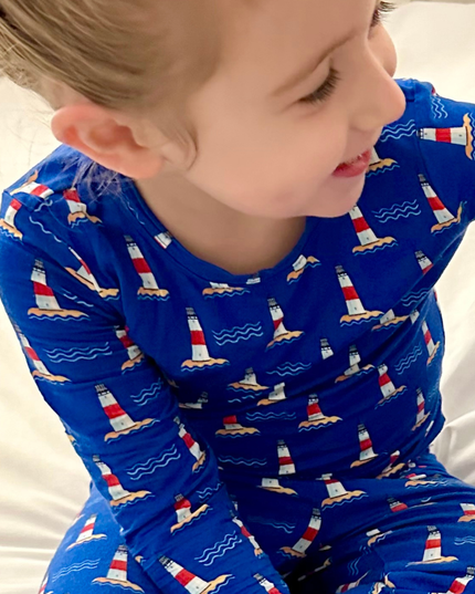 Child wearing blue pajamas with lighthouse pattern on a white background