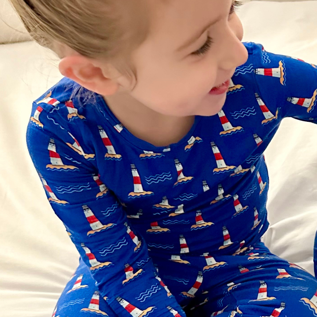 Child wearing blue pajamas with lighthouse pattern on a white background