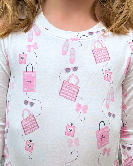 White long-sleeve shirt with pink handbag and accessory pattern worn by a person.