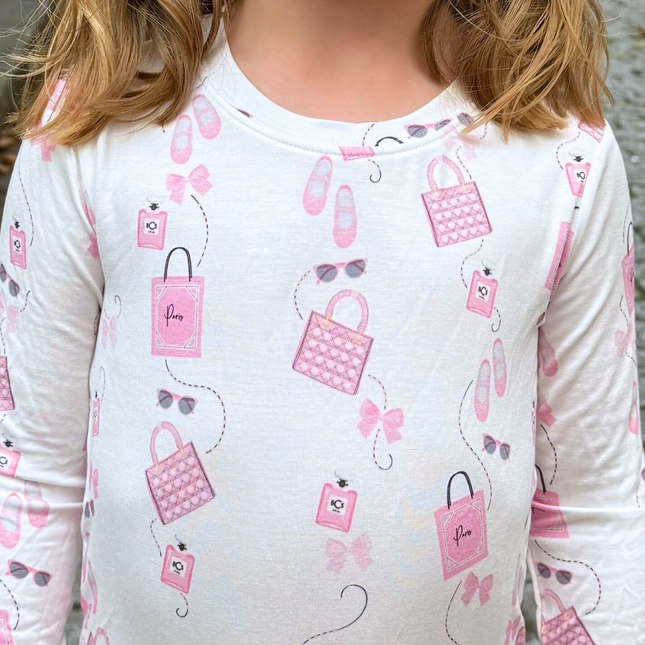White long-sleeve shirt with pink handbag and accessory pattern worn by a person.
