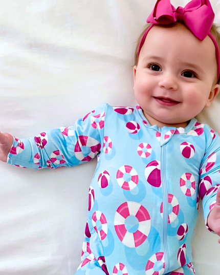 Baby wearing a colorful onesie with a pink bow on a white background
