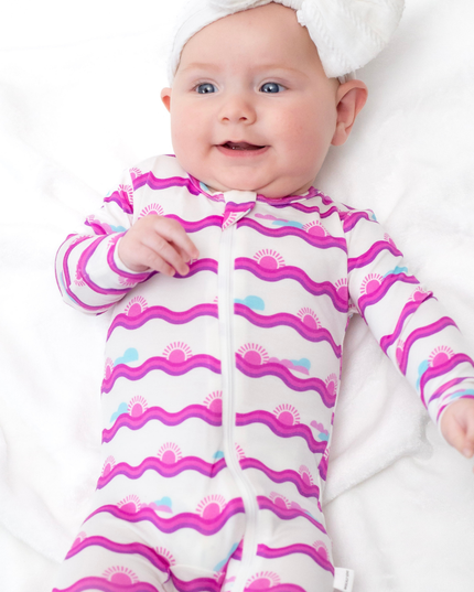 Baby wearing a pink and white patterned onesie on a white background