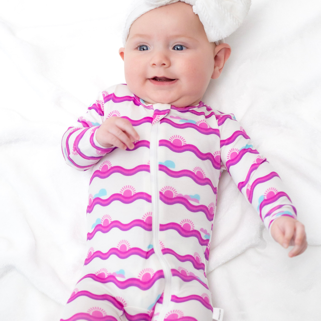 Baby wearing a pink and white patterned onesie on a white background