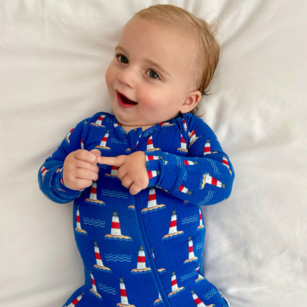 Child wearing a blue onesie with lighthouse pattern on a white background