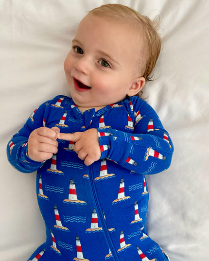 Child wearing a blue onesie with lighthouse pattern on a white background